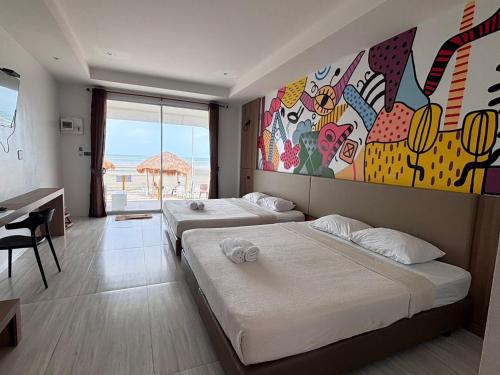 two beds in a room with a painting on the wall at De Mer Resort Rayong in Ban Ao Makham Pom