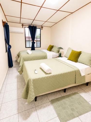 three beds in a room with blue curtains at Gosen Stays in Antiguo Cuscatlán