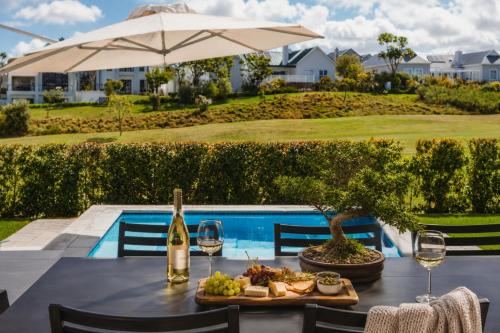 a table with wine glasses and food next to a pool at Moorlands Manor in George