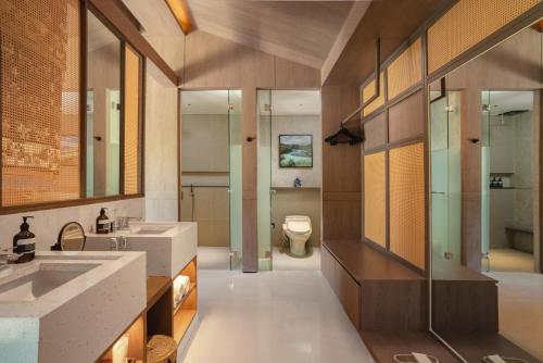 a bathroom with two sinks and a toilet in it at Nuju Uluwatu - Adults Only in Uluwatu