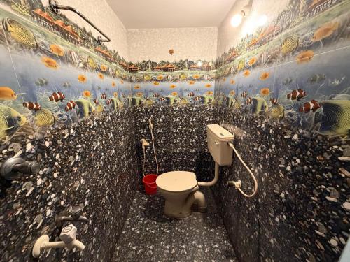 a bathroom with a toilet with fish painted on the wall at Serinity Saral in Pondicherry