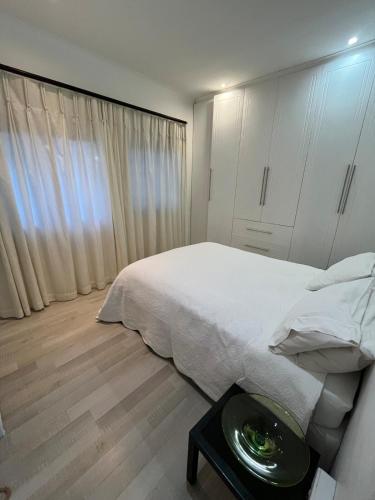 a white bedroom with a bed and a table at Private Retreat in Gordonʼs Bay