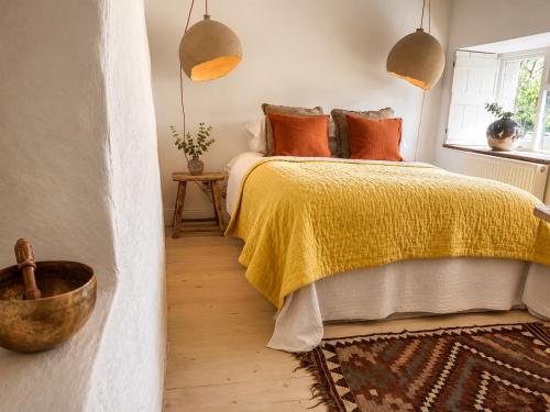 a bedroom with a bed with a yellow blanket and orange pillows at Wester Auchraw Croft B&B in Lochearnhead
