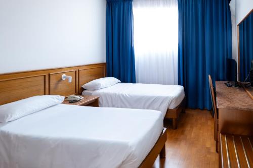 a hotel room with two beds and a window at Hotel Cavallino in Faenza