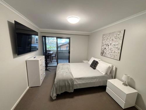 a bedroom with a bed and a desk and a window at Jubilee Apartment 08 - Bring your own linen in South West Rocks