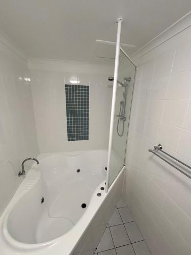 a white bathroom with a tub and a shower at Jubilee Apartment 08 - Bring your own linen in South West Rocks