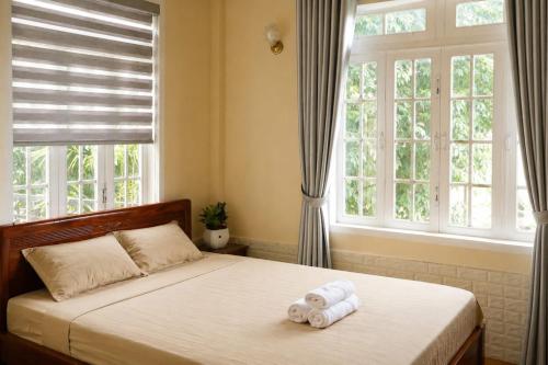 a bedroom with a bed with two rolled towels on it at Thềm Homestay in Da Thien