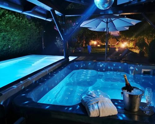 a hot tub in a backyard at night with a bottle of champagne at Dura Guesthouse, Garden Wellness Retreat near the Tisza River in Paszab