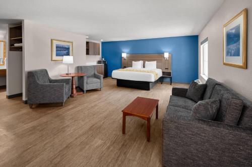 a hotel room with a bed and a couch and chair at Baymont by Wyndham Salida in Salida