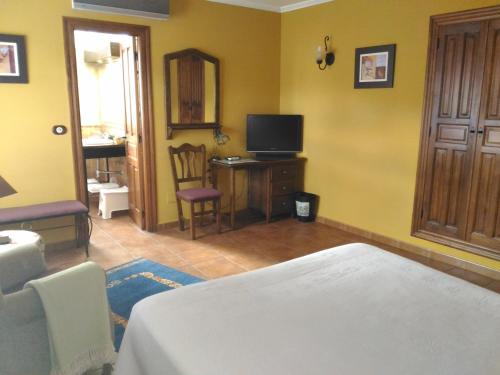 a bedroom with a bed and a desk with a television at Posada Carpe Diem in Liérganes