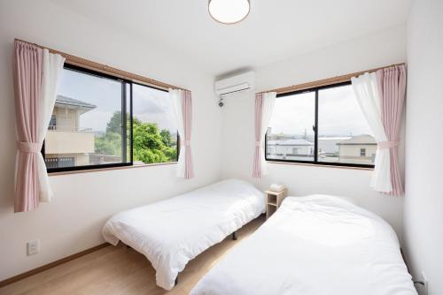 two beds in a white room with windows at Fujiyama Stay101 in Fujinomiya