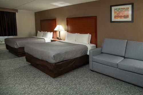 a hotel room with two beds and a couch at Quality Inn Stadium Area Green Bay Stadium in Green Bay