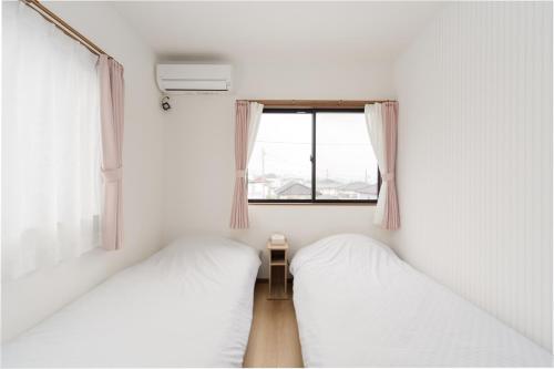 two beds in a small room with a window at Fujiyama Stay102 in Fujinomiya