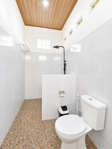 a white bathroom with a toilet in a room at Eleen Bungalow in Tetebatu