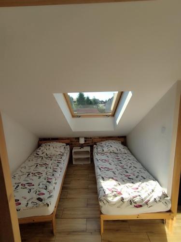 two beds in a small room with a window at Apartament Karmelicka in Wadowice