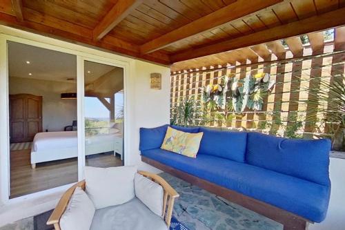 a living room with a blue couch and a bedroom at La Lézardière - Suites de Prestige & Spas Privatifs in Porto-Vecchio