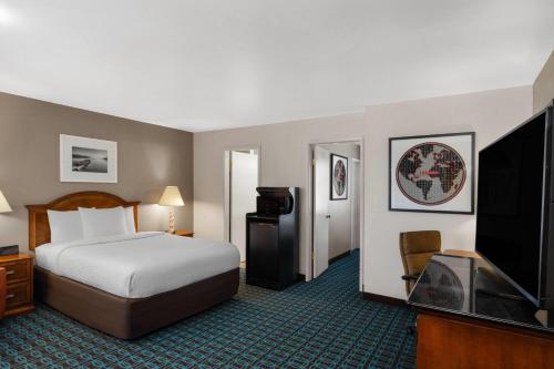 a hotel room with a bed and a flat screen tv at Ramada Bayside Inn & Suites Eureka in Eureka
