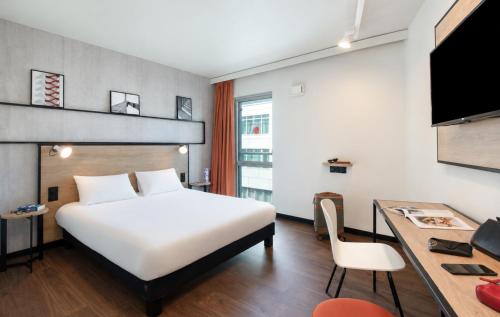 a hotel room with a white bed and a desk at Ibis Clermont-Ferrand Centre Stade in Clermont-Ferrand