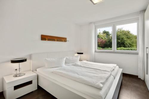 a white bedroom with a white bed and a window at Ferienwohnung Landblick im Markgräflerland mit kostenlosem Parkplatz in Bad Bellingen