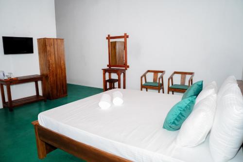 a white bed with pillows and chairs in a room at Circle Edge Resort in Kandy