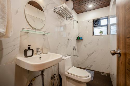 a bathroom with a sink and a toilet and a mirror at Go Offline Homes - Designer 2BHK with Pool Near Candolim in Parra