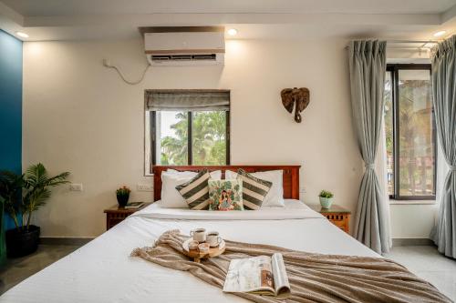 a bedroom with a large white bed with books on it at Go Offline Homes - Designer 2BHK with Pool Near Candolim in Parra
