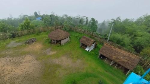 eine Gruppe von Gebäuden mit Grasdächern auf einem Feld in der Unterkunft Hotel Nigale in Dhankuta