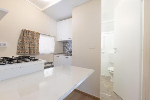 a white kitchen with a stove and a sink at Camping Car Palmasera in Cala Gonone