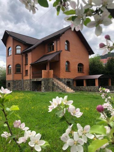a large brick house in a field of flowers at Котедж Гірський in Yaremche