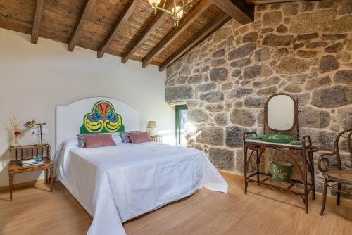 a bedroom with a bed in a stone wall at Casa do Capitan cdc in Leiro