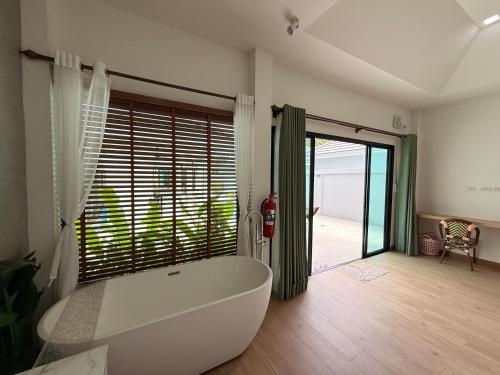 a large white tub in a bathroom with a sliding glass door at Aonang nine poolvilla resort in Ao Nang 