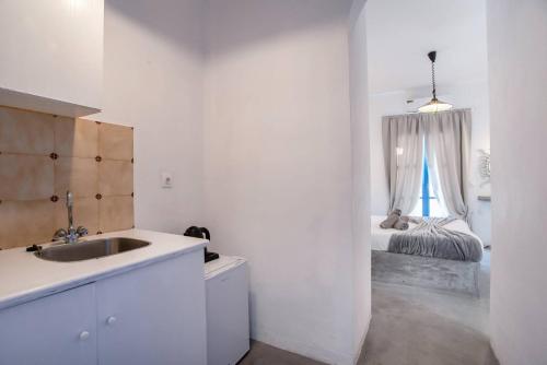 a white kitchen with a sink and a bed at Pleasure Blackbeach Studios in Perissa