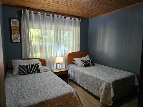 two beds in a room with a window at Habitación Suite in Chimbarongo
