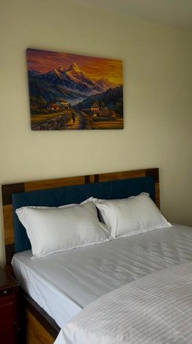 a bed with two white pillows and a painting on the wall at Aranya Villa in Bākhri Kharka