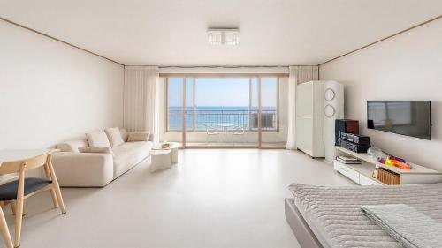 a white living room with a view of the ocean at Pohang Baritdol Pension in Pohang