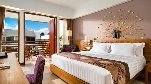 a bedroom with a bed and a balcony with a table at Sun Island Hotel & Spa Kuta in Kuta