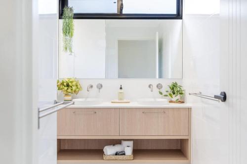 a bathroom with two sinks and a mirror at The Luxe Breeze Bungalow in Hervey Bay