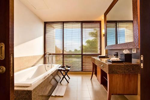 a bathroom with a tub and a large window at Sun Island Hotel & Spa Kuta in Kuta