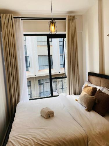 a bed with a stuffed animal on it in front of a window at Nomads nest suites in Kiambu