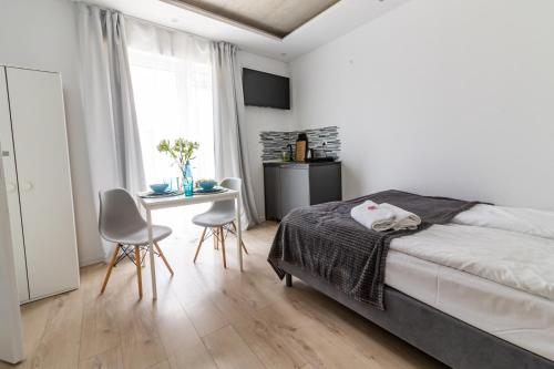 a bedroom with a bed and a table and chairs at BLOMMA Niechorze in Niechorze