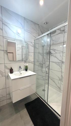 a white bathroom with a sink and a shower at Le Cocon Signature in Château-Thierry