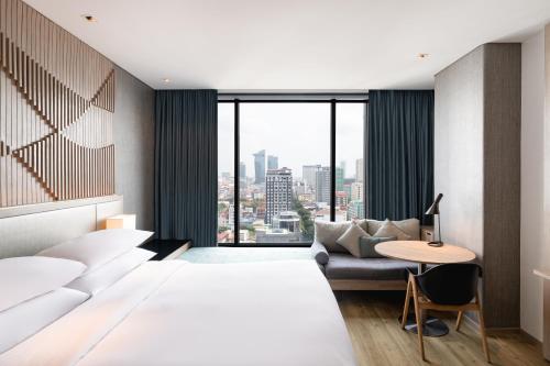 a hotel room with a large bed and a table at Courtyard by Marriott Phnom Penh in Phnom Penh