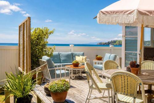 a patio with a table and chairs and the ocean at Beachfront Bliss - Stay Waiheke in Onetangi