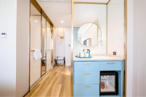 a bathroom with a blue vanity and a mirror at Manxin Hotel Suzhou Jinfeng Road in Suzhou
