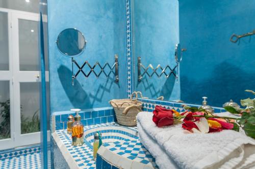 een blauwe betegelde badkamer met 2 handdoeken op een bad bij Astra Damus Hotel in Marrakesh