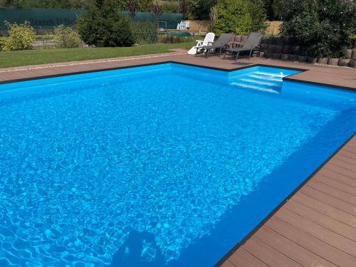 a swimming pool with blue water in a backyard at Statek U Dubu in Svojetín