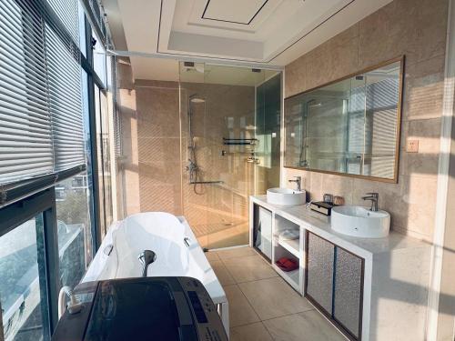 a bathroom with a tub and two sinks and a shower at 伟信名人酒店 in Sihanoukville