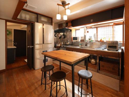 a kitchen with a wooden table and stools in it at Ukiwa Guest House in Shimoda