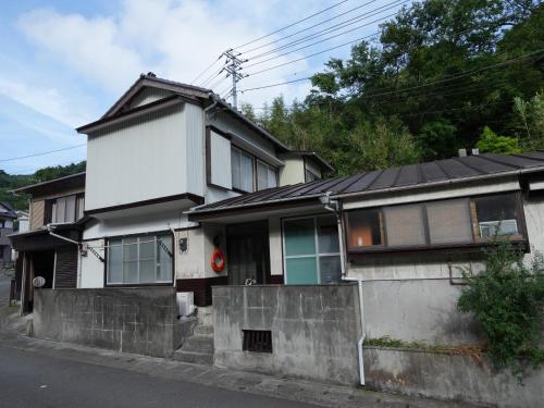 a white house with a black roof at Ukiwa Guest House in Shimoda