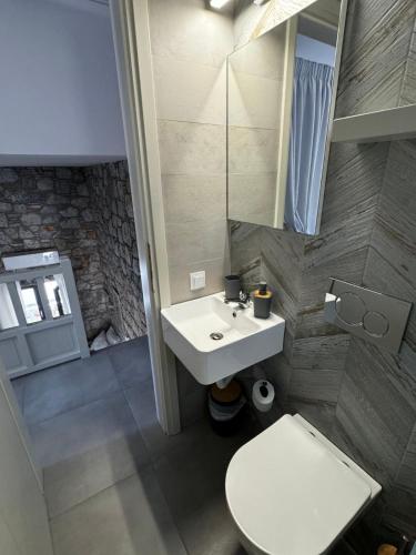 a bathroom with a sink and a toilet and a mirror at Casa Petra Astypalea in Astypalaia